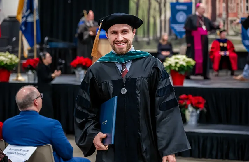 A newly hooded graduate returns to his seat.