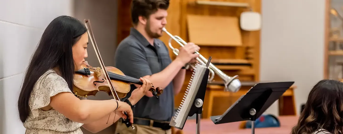 A man playing the trumpet and a woman playing the violin.